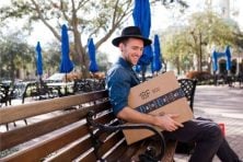 A man smiles while holding onto an Amazon box.