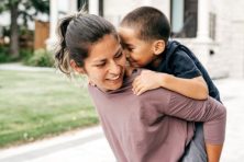 A woman carries her son on her back.