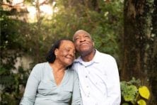 A senior citizen couple embrace in their garden.