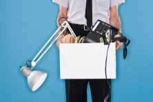 A stock photo shows a man carried a box full of office items.