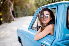 A woman drives a blue pickup truck.