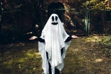 A woman wears a ghost costume.