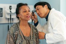 A woman gets her ear checked by a doctor.