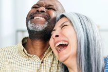 A married couple laugh while snuggling together.
