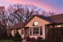 A rainbow forms over a purple sky near a home in the suburbs.