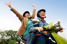 A retired couple enjoy a ride on a scooter.