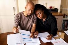 A couple lean into one another as they review their finances at a table.