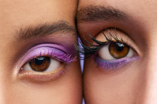 The eye of two women are photographed wearing purple eye shadow.