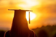 A graduate looks off into the sunset.