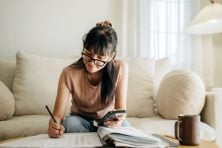 A woman gets her finances together while sitting on her couch.