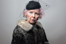 A wealthy senior aged woman wearing a black veil looks angry.