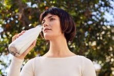 A woman drinks from a reusable water bottle.