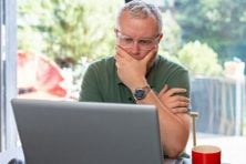 A man looks perplexed as he looks at his laptop.