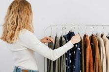 A woman looks at clothing on a display rack in a clothing store.