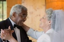 A senior citizen male and female have their first dance at their wedding.