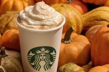 A pumpkin spiced latte is photographed with pumpkins all around it.