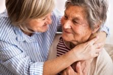 A daughter hugs her elderly mother.