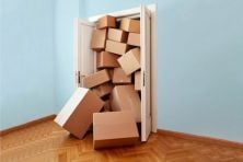 A stack of boxes falls out of a closet door.
