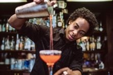 A man pours a mixed drink into a glass.