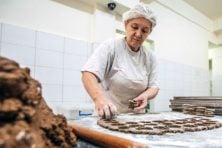 A woman rolls out dough as she works at a bakery.