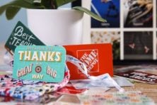 Gift cards sit on a table and also propped up on a plant.