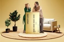 A couple recline against a giant credit card in their living room.