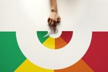 A woman holds her finger on a pointer that points to green in a color wheel meant to represent a person's credit score.