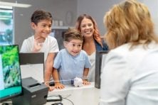 A mother visits the bank with her two sons who are looking to put their savings into a bank account.