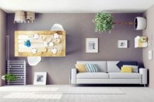 An empty living room is on display with a couch and upside down furniture such as a table and potted plants.