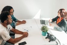 A man and woman sit down with someone at a credit union.