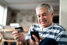 A man uses a credit card to make an online purchase.