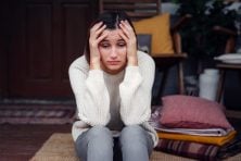 A woman looks stressed out while sitting on her porch.
