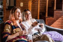 Two women laugh as they watch television.