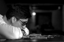 A man puts his head on a desk and looks at money