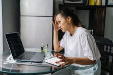 A woman looks at her laptop looking stressed