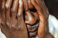 An elderly man overs his face with his hands in an act of confusion.
