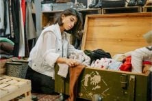 A woman looks through second-hand clothing displayed in a foot locker in a thrift store.