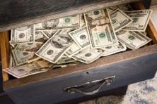 A stash of money sits in a dresser drawer.