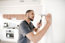 A man places a nail in the wall.