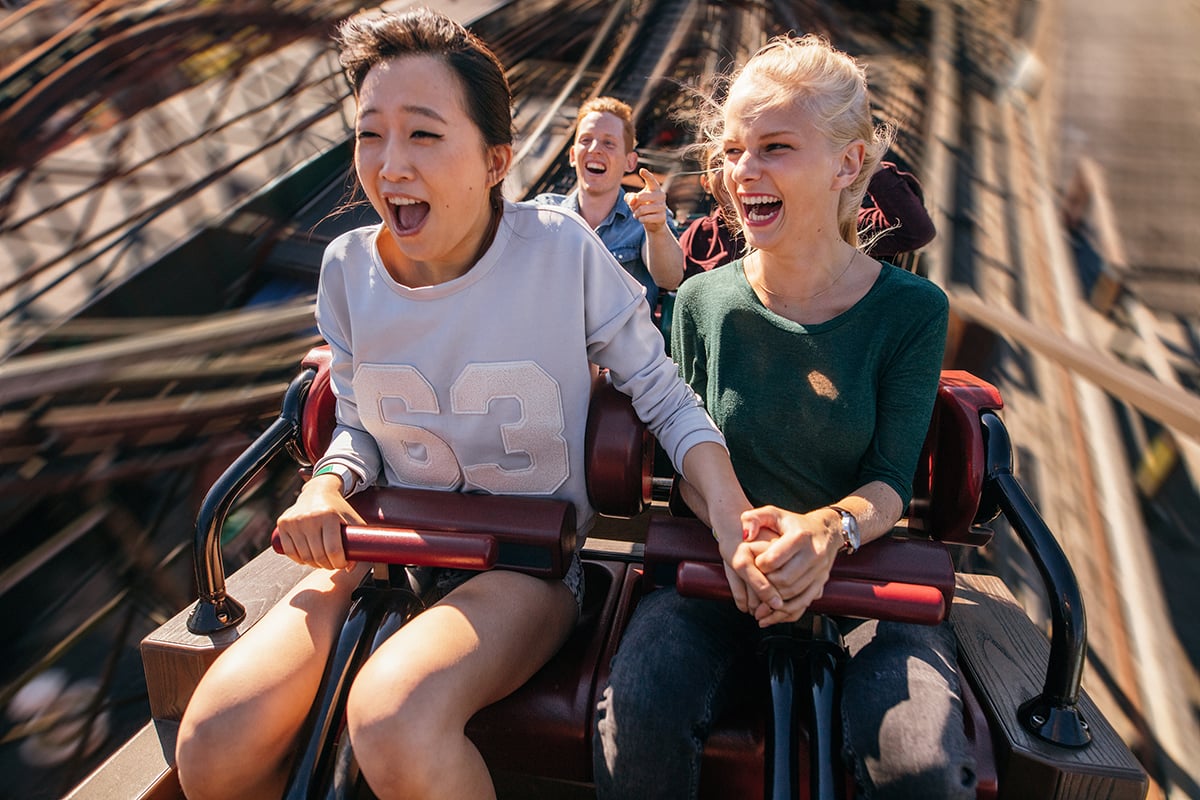 People ride a roller coaster at and amusement park.