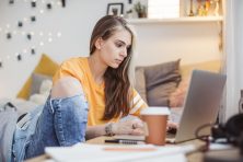 A college students works on her laptop in her dorm room.