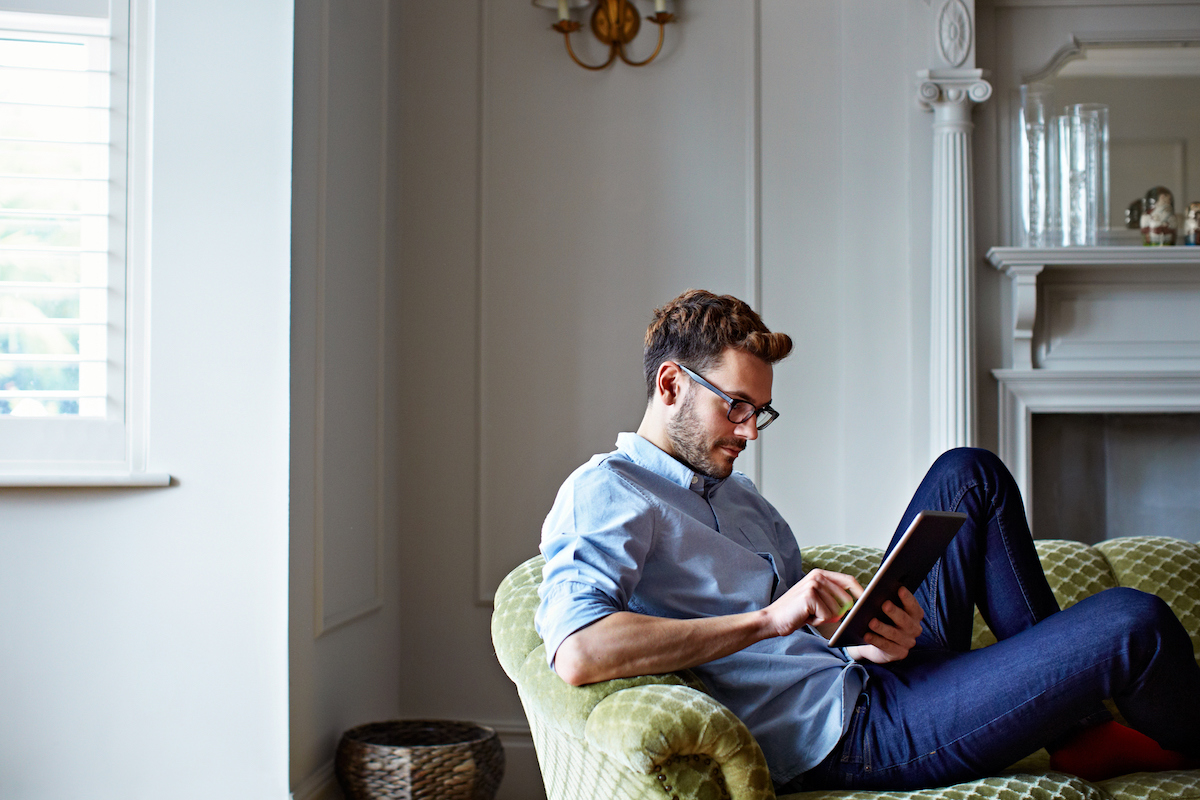 Shot of a young man sitting on his sofa at home using a digital tablet