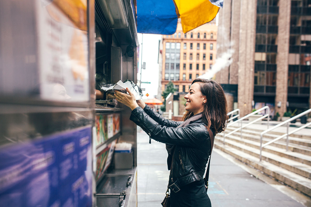 woman buys some lunch from a New York city food cart