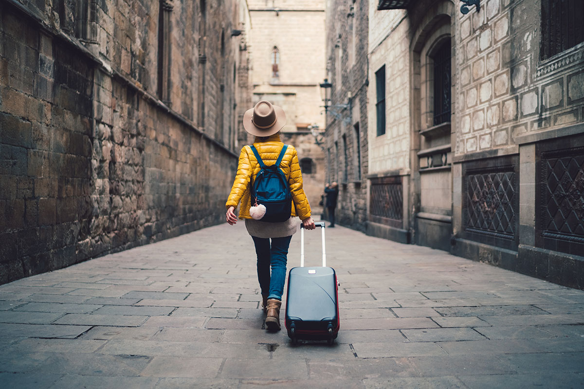 Young woman with suitcase walking at the street in Barcelona