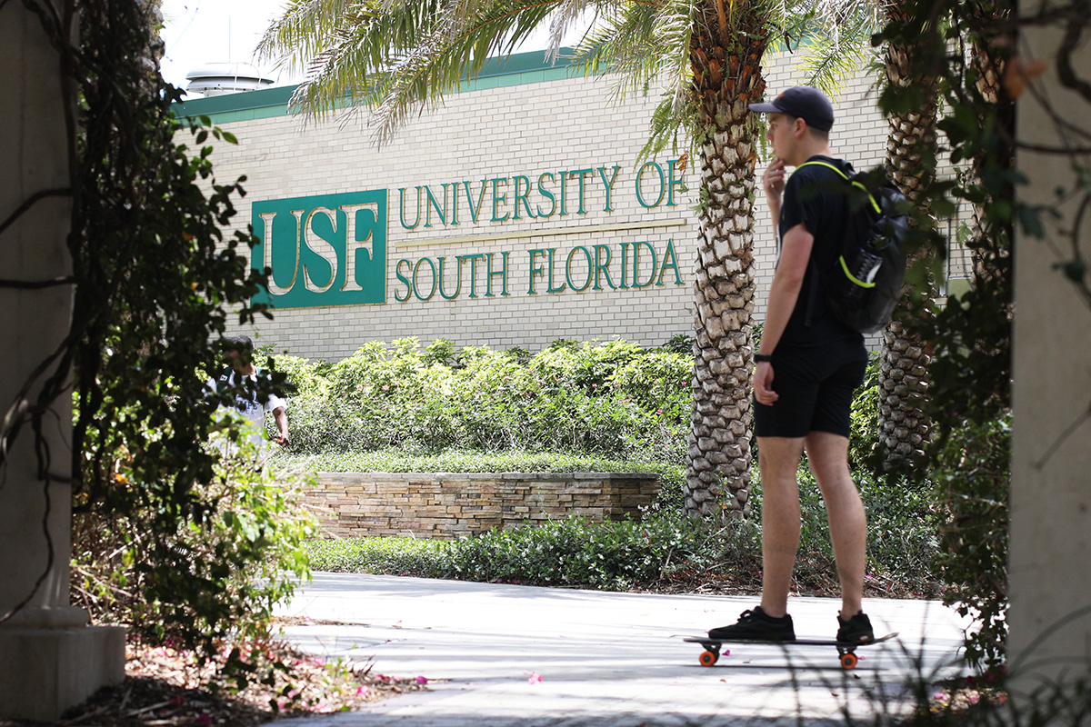 A person skateboards while on his way to class on a college campus.