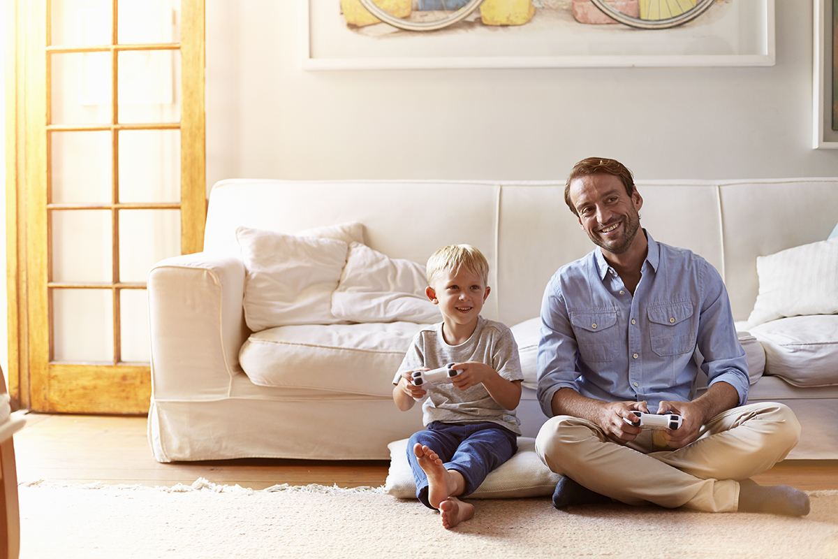 Father and son playing video games together at home