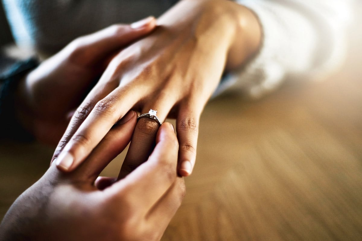 A person places a diamond ring on a woman's finger. 