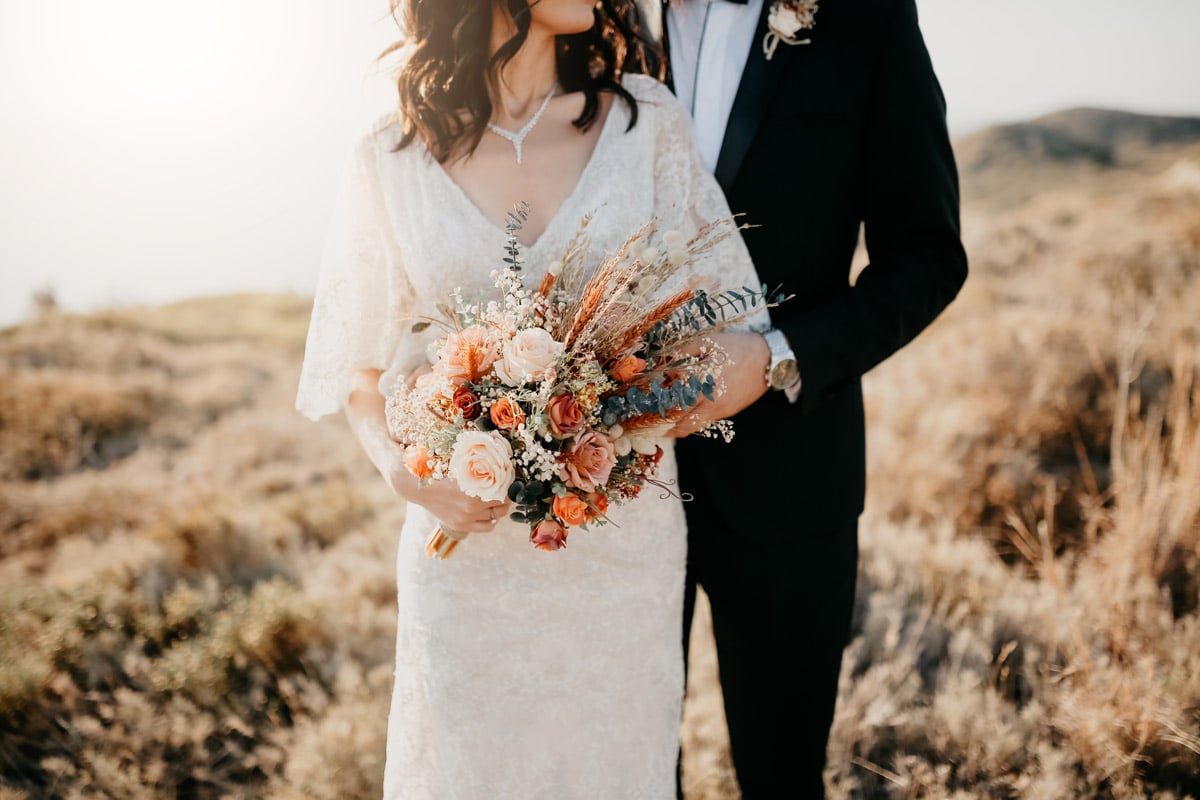 A bride and groom on their wedding day. The bride holds a bouquet of flowers. 