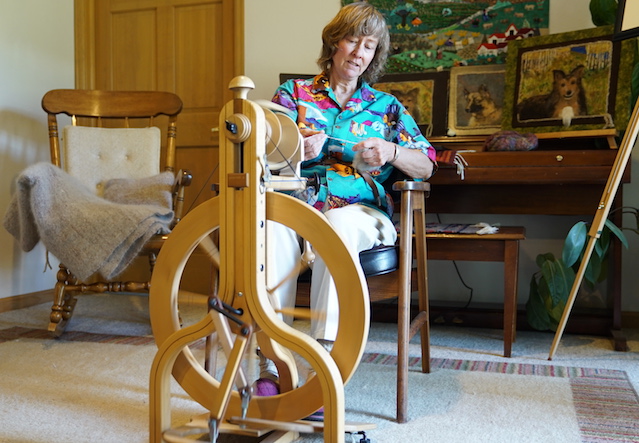 A woman makes a blanket on a loom.