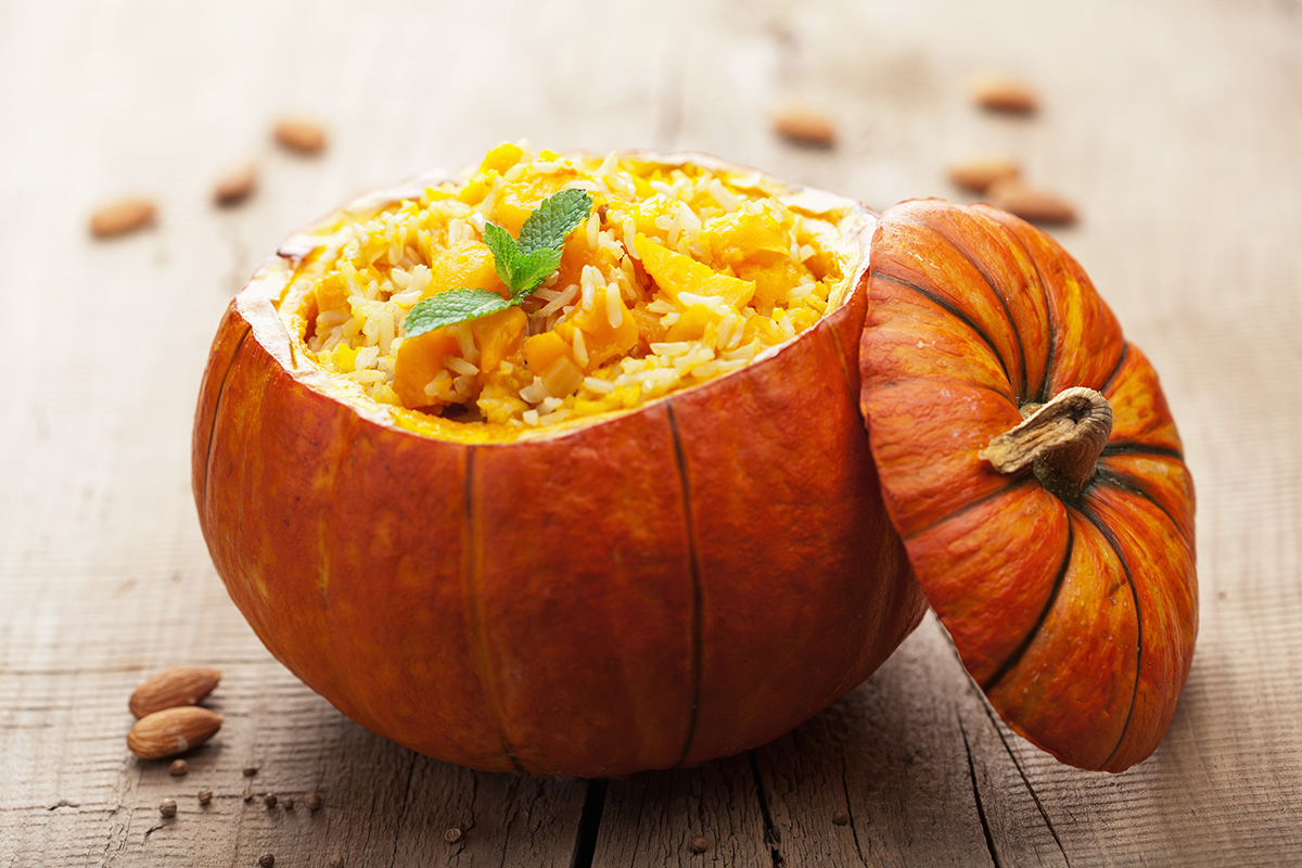 A pumpkin is used as a serving bowl for food.